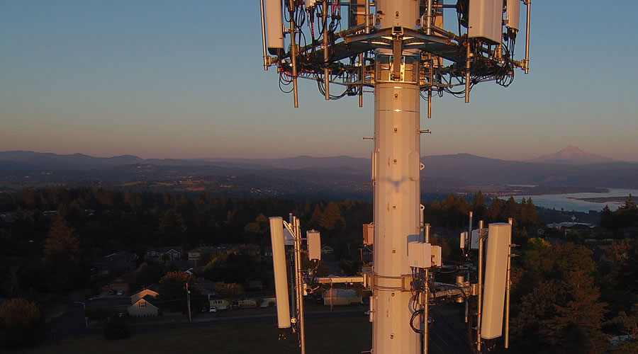 Two antenna clusters on a tower with Mount Hood in the background at sunset.